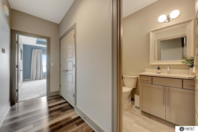 bathroom featuring baseboards, vanity, toilet, and wood finished floors