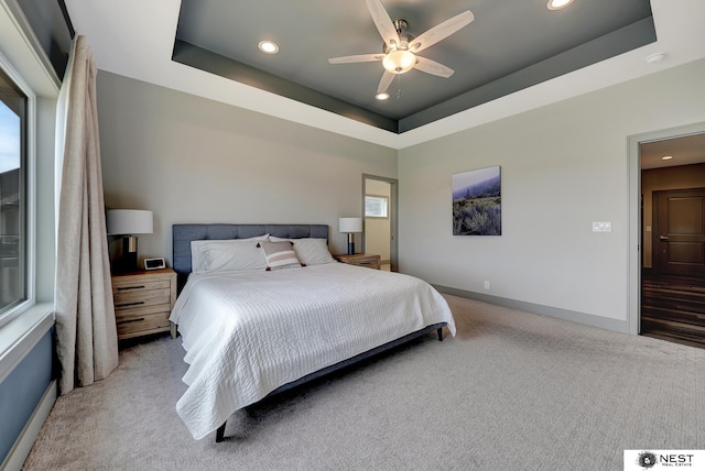 carpeted bedroom with baseboards, a tray ceiling, and recessed lighting