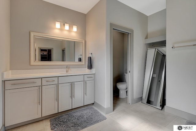 bathroom featuring toilet, tile patterned floors, baseboards, and vanity