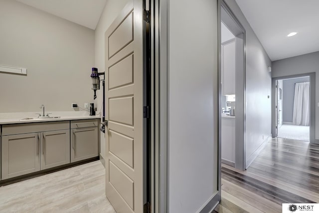 interior space with light wood finished floors, baseboards, a sink, and recessed lighting