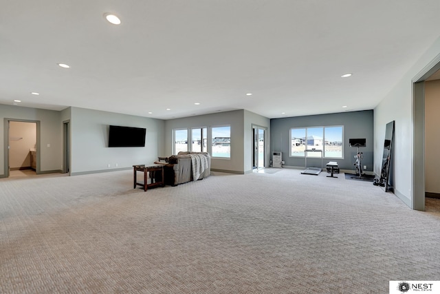 unfurnished living room with recessed lighting, light carpet, plenty of natural light, and baseboards