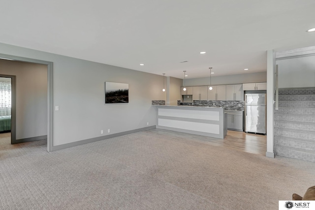 kitchen with light colored carpet, backsplash, and freestanding refrigerator