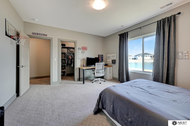 carpeted bedroom with baseboards, visible vents, a walk in closet, and a closet