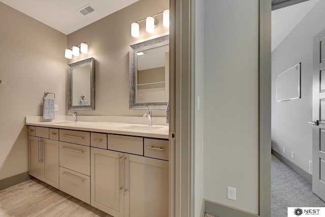 full bath featuring double vanity, baseboards, visible vents, and a sink