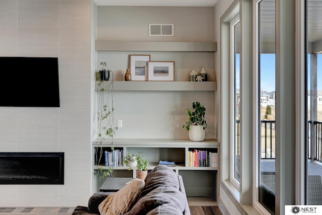 living area featuring a tiled fireplace and visible vents