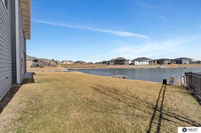 view of yard featuring a water view, fence, and a residential view