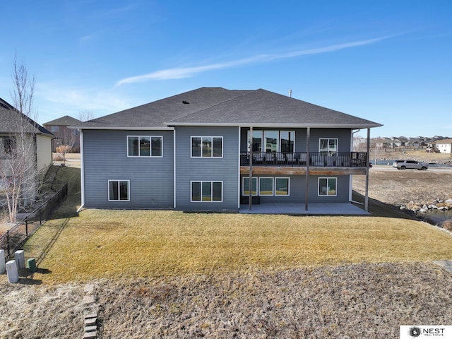 back of house with a shingled roof, a patio area, and a yard