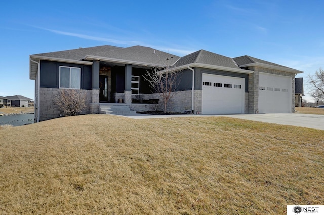 prairie-style home with a front yard, stone siding, an attached garage, and concrete driveway