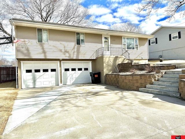 view of front of property featuring an attached garage, fence, and concrete driveway