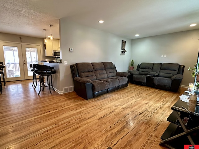 living area with french doors, light wood finished floors, recessed lighting, visible vents, and baseboards