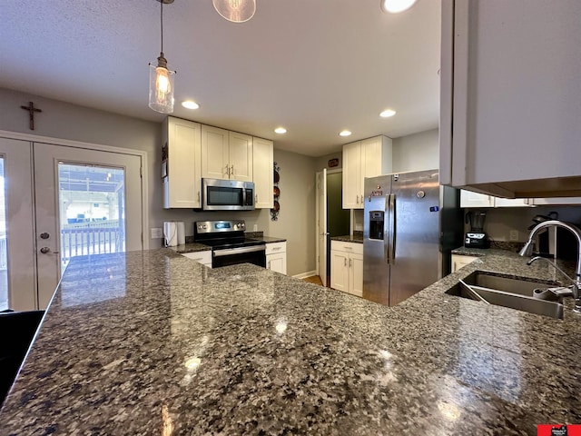 kitchen with stainless steel appliances, white cabinetry, a sink, and a peninsula