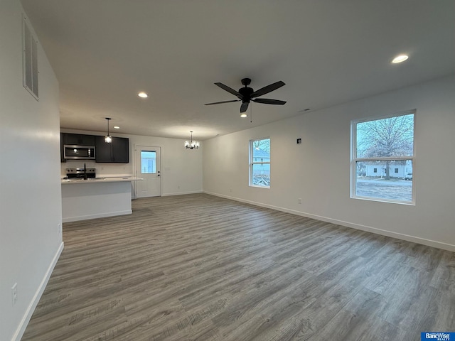 unfurnished living room featuring recessed lighting, visible vents, wood finished floors, baseboards, and ceiling fan with notable chandelier