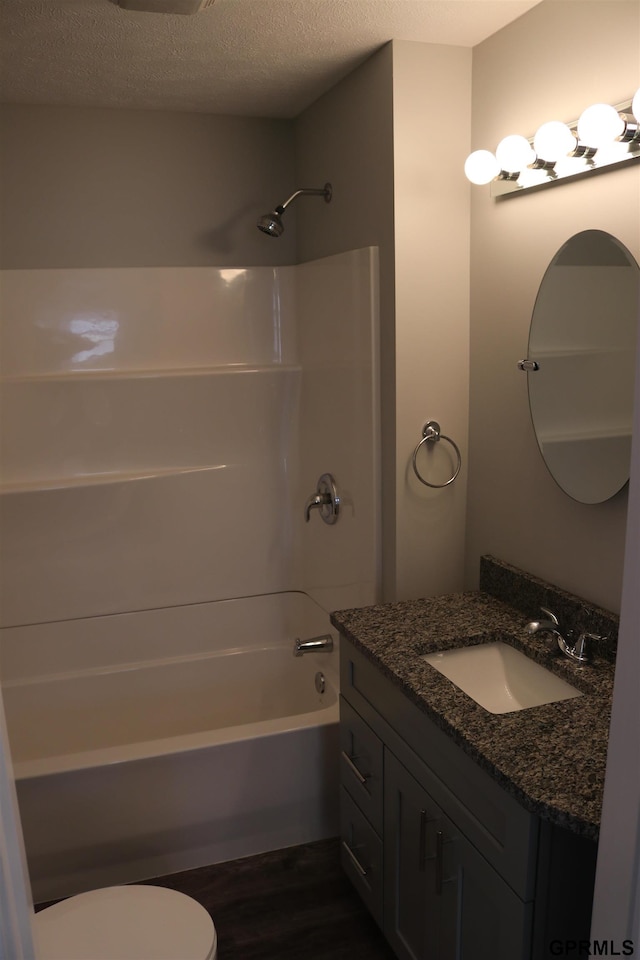 full bathroom featuring shower / bathing tub combination, toilet, a textured ceiling, vanity, and wood finished floors