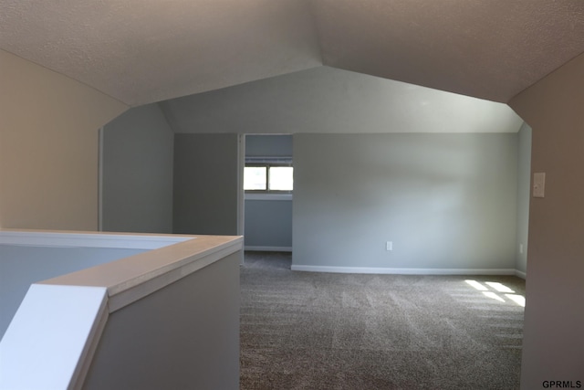 bonus room with vaulted ceiling, a textured ceiling, dark carpet, and baseboards