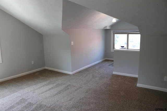 bonus room featuring a textured ceiling, carpet flooring, lofted ceiling, and baseboards