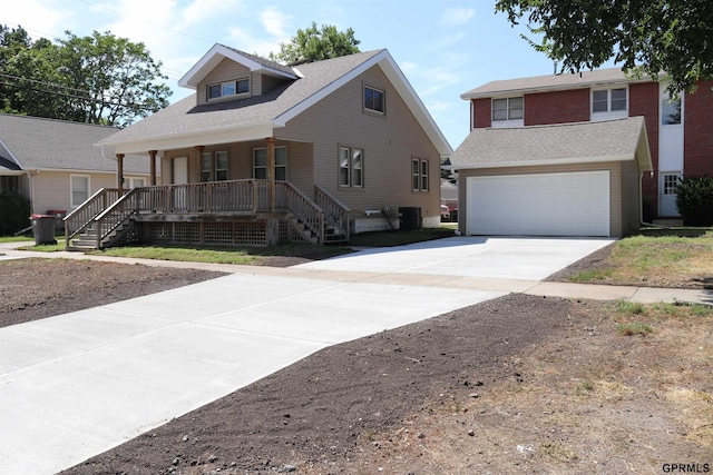 view of front of home with a garage, concrete driveway, stairway, covered porch, and central air condition unit