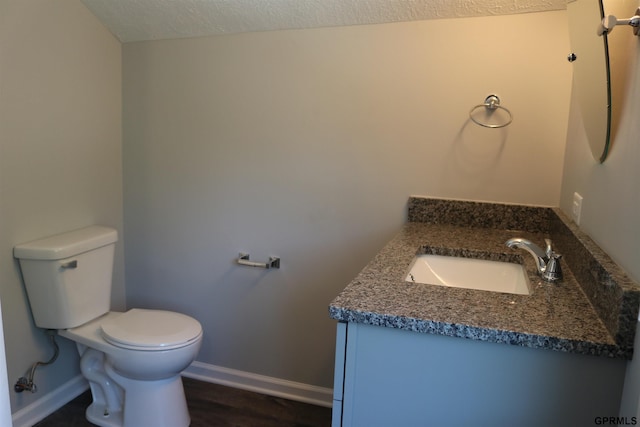 bathroom with baseboards, toilet, wood finished floors, a textured ceiling, and vanity