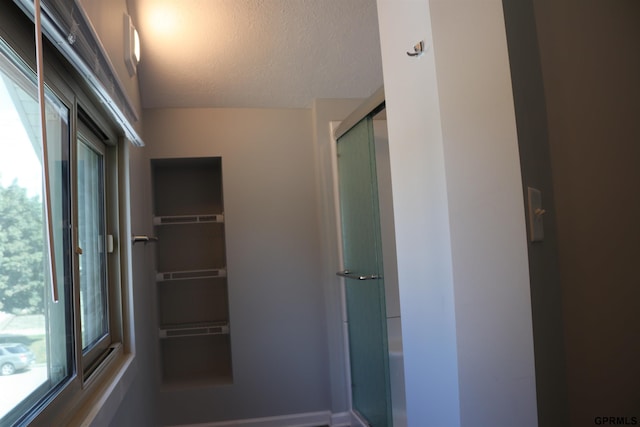 bathroom with a walk in closet, a shower with door, and a textured ceiling