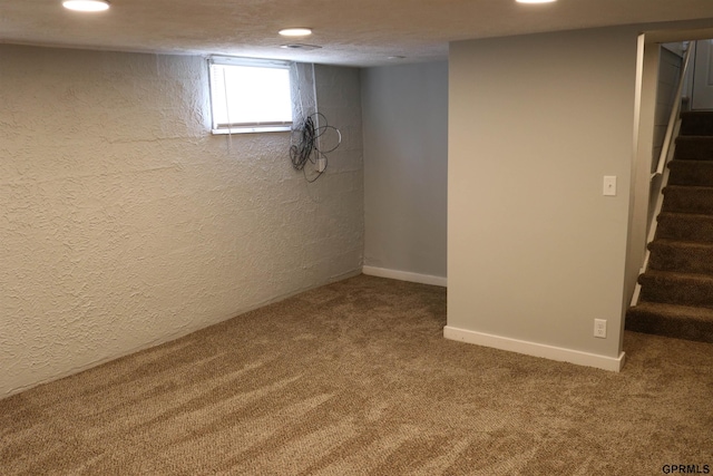 below grade area with baseboards, a textured wall, stairs, carpet flooring, and recessed lighting