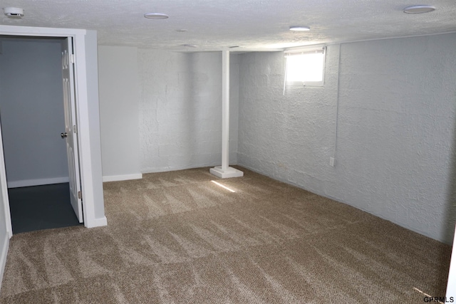 below grade area featuring a textured ceiling, carpet flooring, and a textured wall