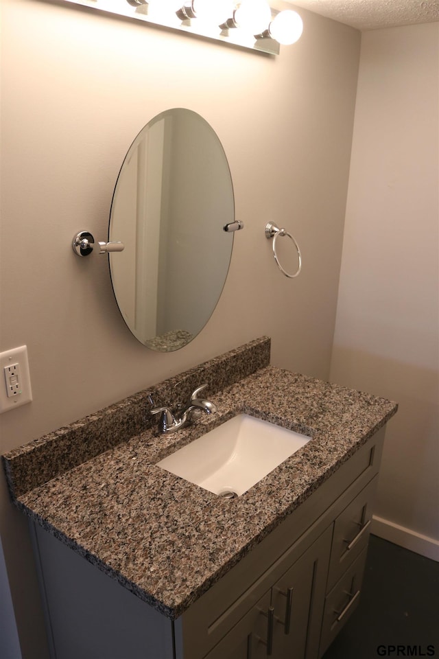 bathroom with a textured ceiling, vanity, and baseboards