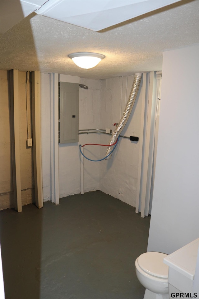 interior space featuring a textured ceiling, toilet, concrete floors, and electric panel