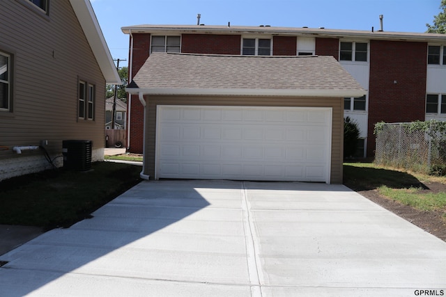 traditional home featuring a garage, driveway, fence, and cooling unit