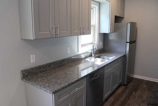 kitchen with dark wood-style flooring, a sink, freestanding refrigerator, light stone countertops, and dishwasher