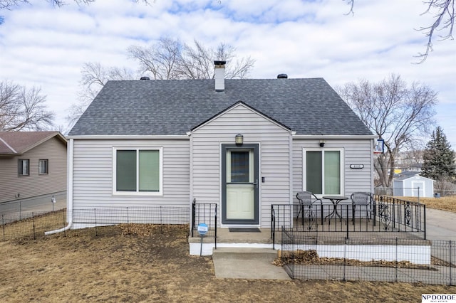 bungalow-style home featuring a shingled roof, fence, and a chimney