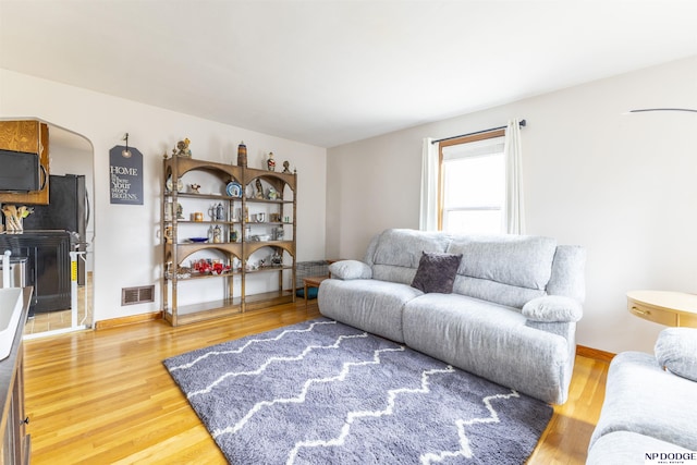 living room featuring visible vents, baseboards, and wood finished floors