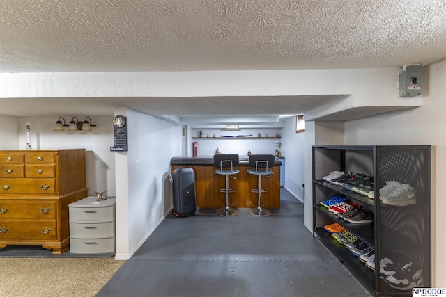 office featuring a dry bar, finished concrete floors, baseboards, and a textured ceiling