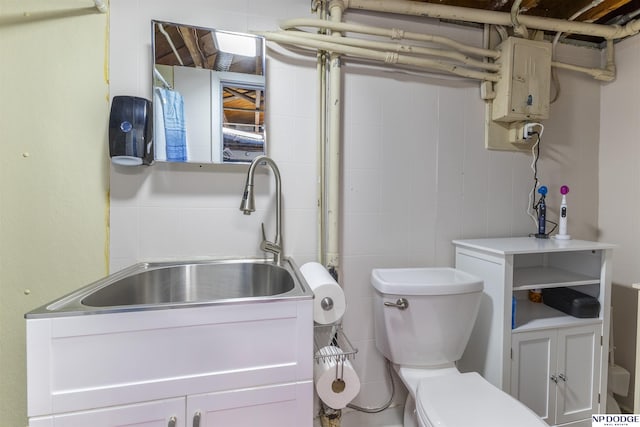 interior space with a sink, tile walls, and toilet