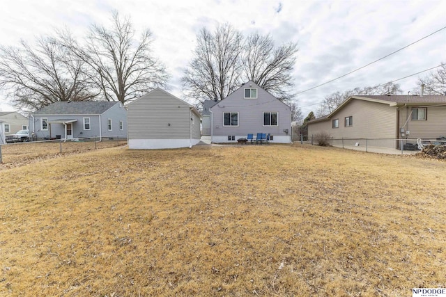 back of property with fence and a lawn