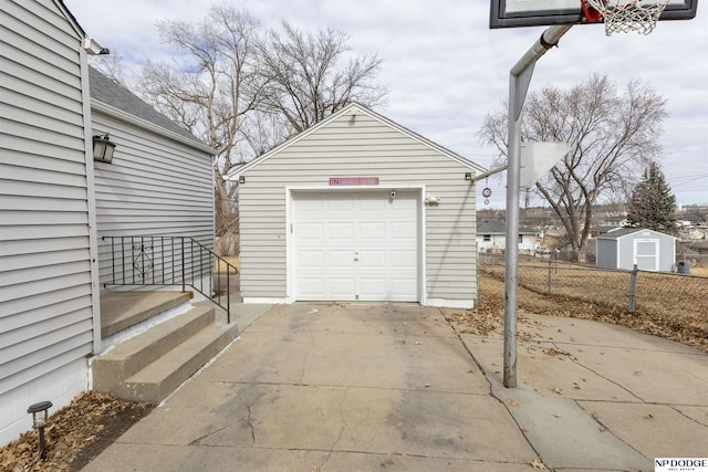 detached garage featuring driveway and fence