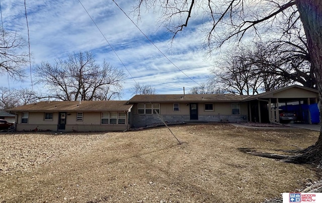 rear view of property with an attached carport and stone siding