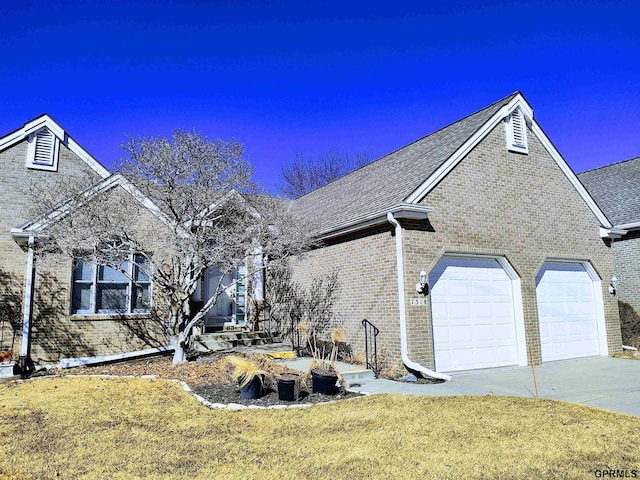 view of front of property featuring an attached garage, brick siding, concrete driveway, roof with shingles, and a front yard