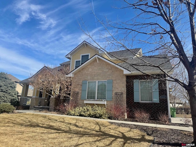 view of front facade featuring stone siding, a front lawn, and brick siding