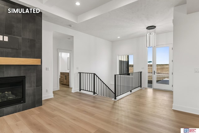 interior space with recessed lighting, a tiled fireplace, wood finished floors, and baseboards