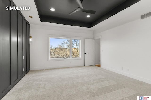 unfurnished bedroom with a tray ceiling, recessed lighting, light colored carpet, visible vents, and baseboards