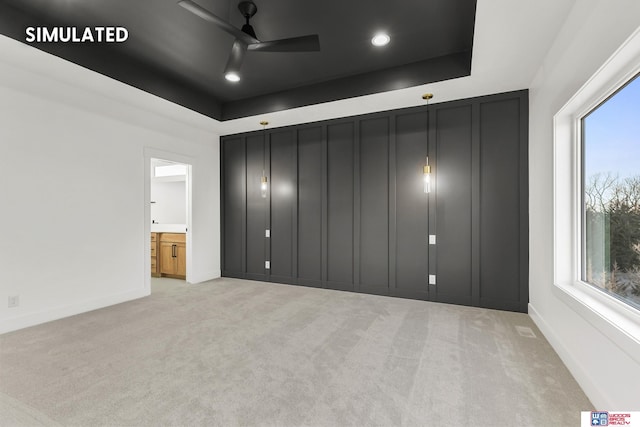 unfurnished bedroom featuring a tray ceiling, light colored carpet, and baseboards