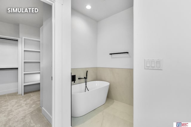 bathroom with recessed lighting, a freestanding bath, and a spacious closet