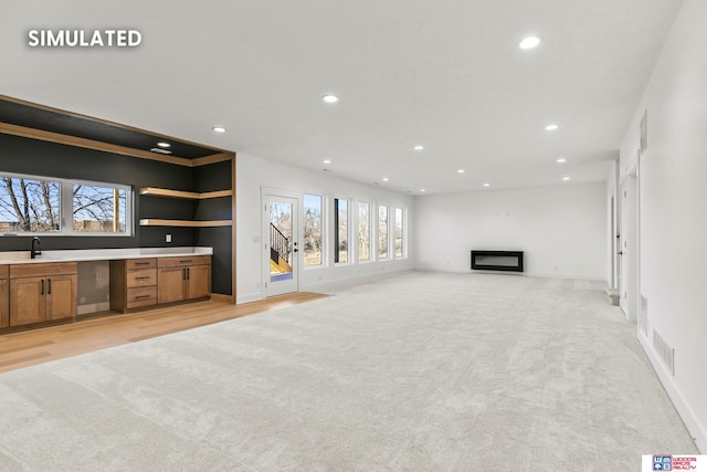 living room with light carpet, recessed lighting, and a glass covered fireplace