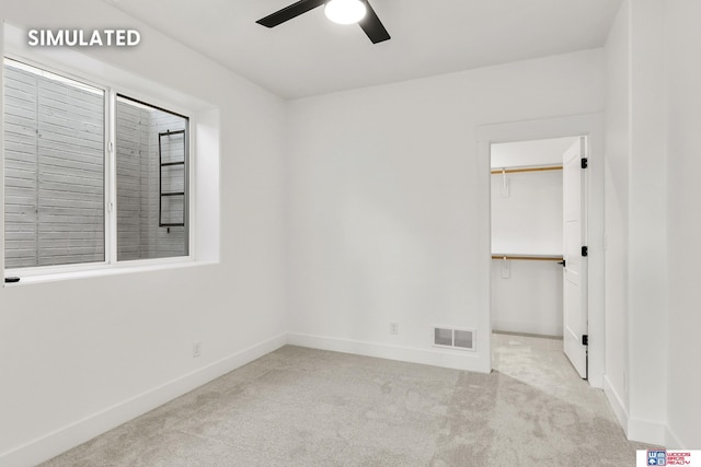 unfurnished bedroom with carpet, a spacious closet, visible vents, and baseboards