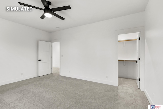 unfurnished bedroom featuring a ceiling fan, carpet flooring, a spacious closet, and baseboards