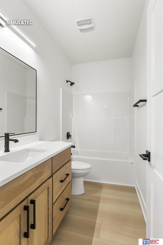 full bathroom with toilet, wood finished floors, visible vents, vanity, and shower / washtub combination