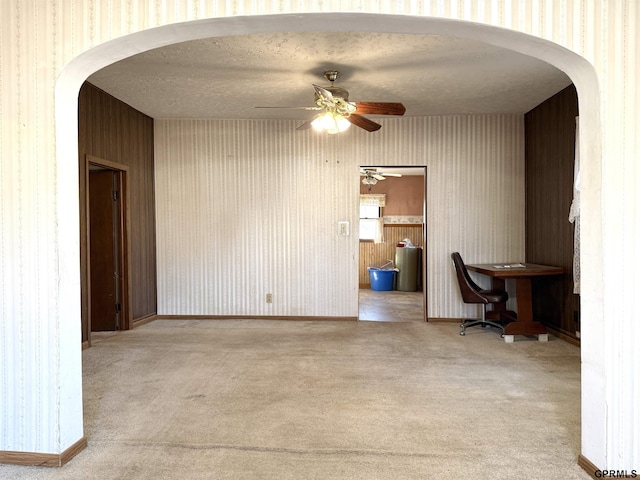 home office featuring carpet floors, arched walkways, and wallpapered walls