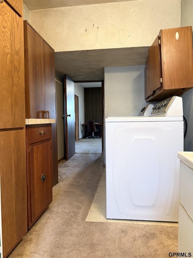 kitchen featuring washer / clothes dryer, brown cabinets, light countertops, and light colored carpet