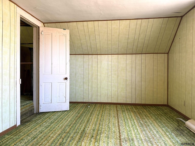 additional living space with lofted ceiling, wooden walls, baseboards, and carpet flooring