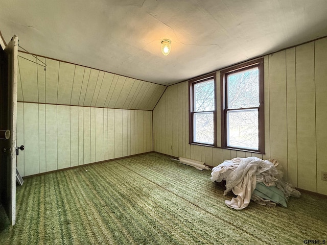 bonus room featuring lofted ceiling, carpet, wooden walls, and baseboards