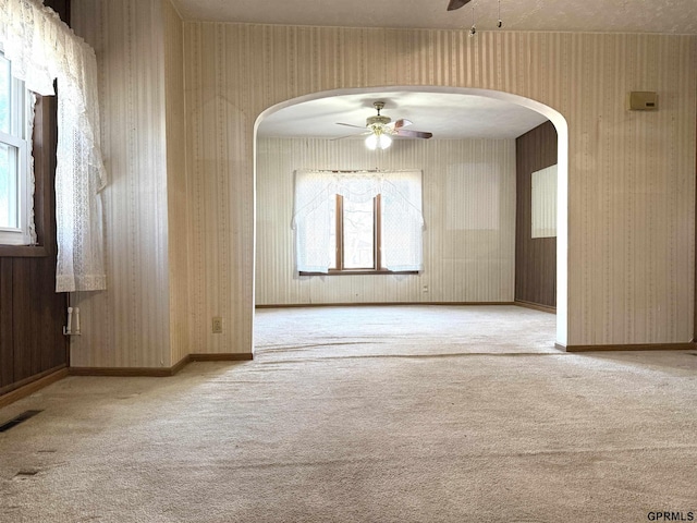 carpeted spare room with a ceiling fan, visible vents, baseboards, and wallpapered walls